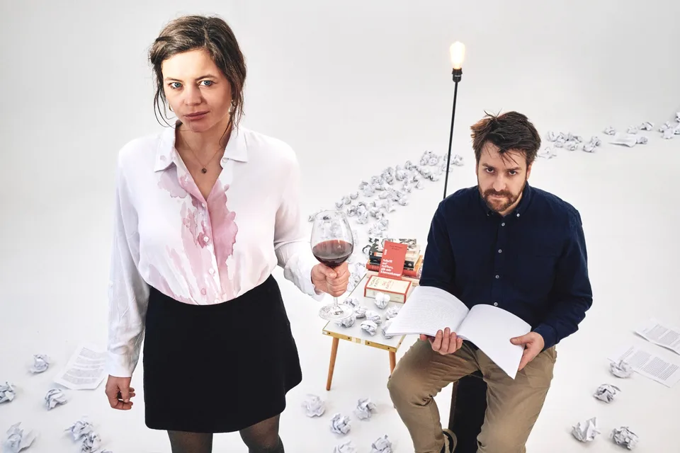 Susanne Aßmann mit Weinglas und Robert Schwarz mit Manuskript zwischen zerknüllten Drehbuchseiten im Studio